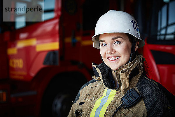 Porträt einer lächelnden Feuerwehrfrau mit Helm in der Feuerwache