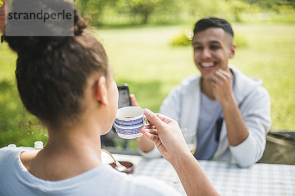 Lächelnder Teenager  der eine Freundin beim Kaffeetrinken im Restaurant ansieht