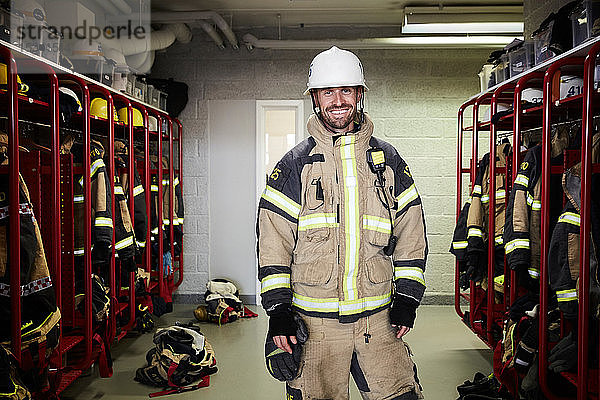 Porträt eines lächelnden männlichen Feuerwehrmannes in der Umkleidekabine der Feuerwache