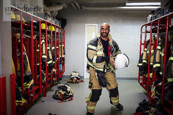 Männlicher Feuerwehrmann mit Arbeitshelm in der Umkleidekabine der Feuerwache