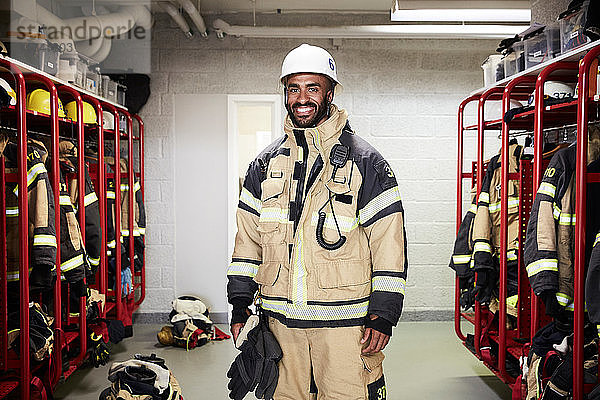 Porträt eines lächelnden männlichen Feuerwehrmannes in der Umkleidekabine der Feuerwache