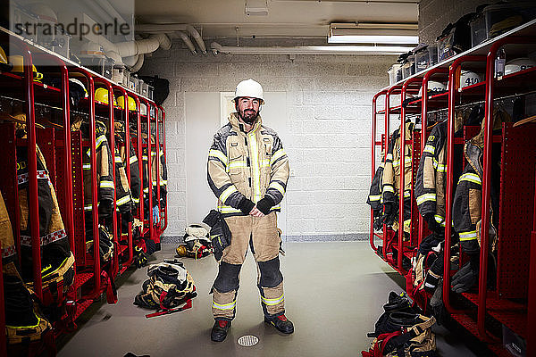 Männlicher Feuerwehrmann in voller Länge in der Umkleidekabine der Feuerwache stehend