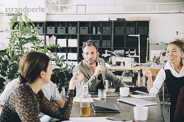 Kreative Geschäftsleute diskutieren bei Tisch im Büro