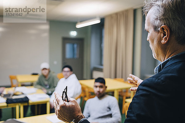 Männlicher Lehrer gestikuliert beim Unterrichten von Schülern im Klassenzimmer