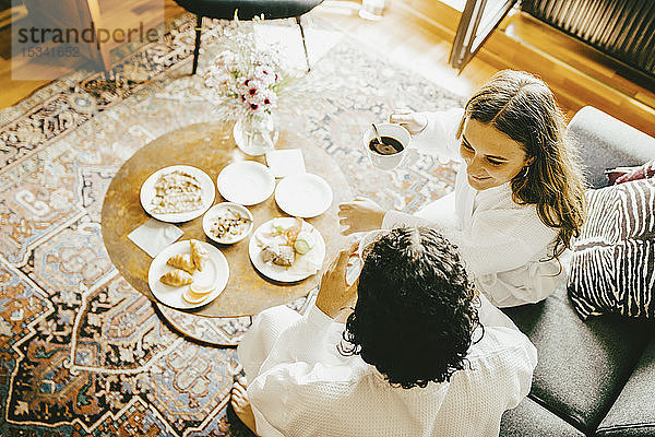 Schrägaufnahme eines jungen Paares beim Frühstück im Hotelzimmer