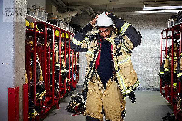 Mittlerer erwachsener Feuerwehrmann mit Arbeitshelm in der Umkleidekabine der Feuerwache