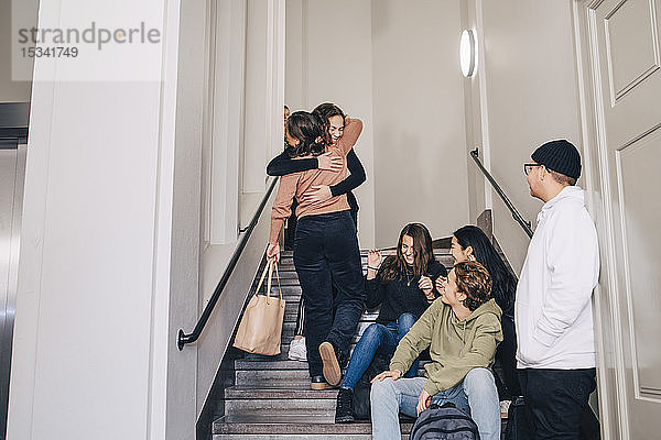 Teenager auf der Suche nach weiblichen Klassenkameradinnen  die sich auf Stufen in der High School umarmen