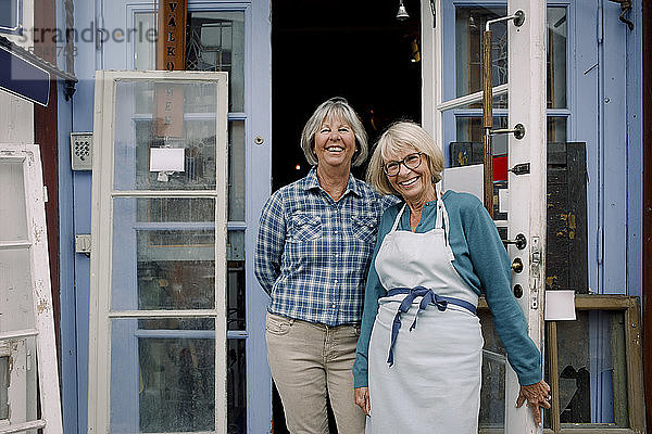 Porträt von fröhlichen Besitzerinnen  die am Eingang des Geschäfts stehen