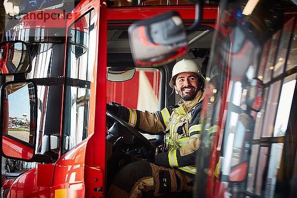 Feuerwehrmann schaut weg  während er im Feuerwehrauto der Feuerwache sitzt