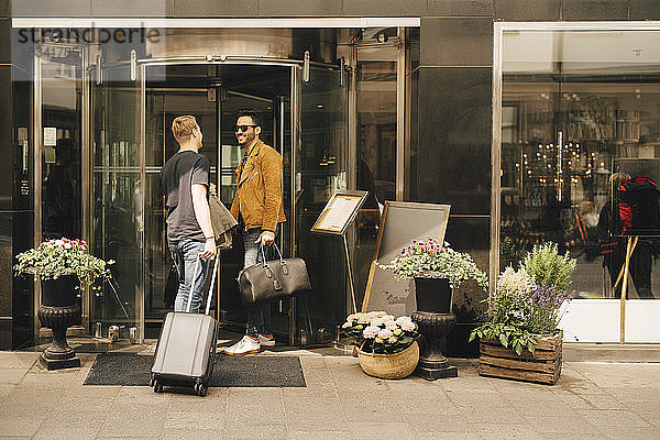 Freunde unterhalten sich  während sie vor der Tür eines Hotels in der Stadt stehen