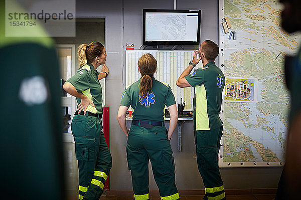 Männliche und weibliche Rettungssanitäter diskutieren während sie im Krankenhaus auf den Bildschirm schauen