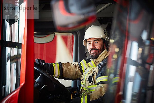 Porträt eines selbstbewussten männlichen Feuerwehrmannes  der im Feuerwehrauto auf der Feuerwache sitzt