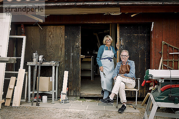 Ganzfiguriges Porträt von lächelnden älteren Mitarbeitern am Eingang zum Baumarkt