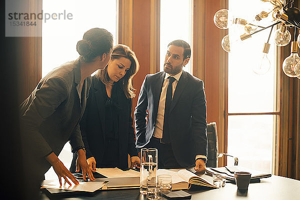 Männliche und weibliche Juristen diskutieren über Dokumente bei Bürotreffen
