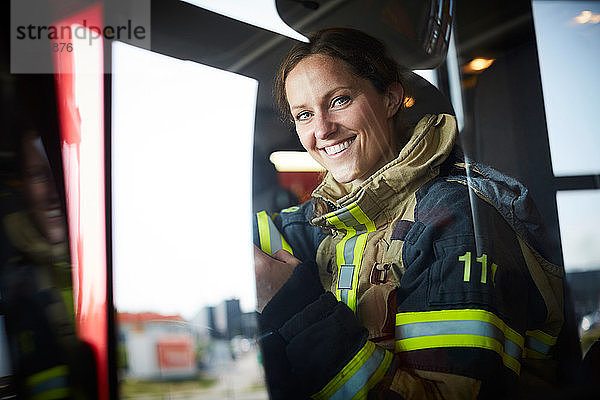 Porträt einer lächelnden Feuerwehrfrau im Feuerwehrauto sitzend