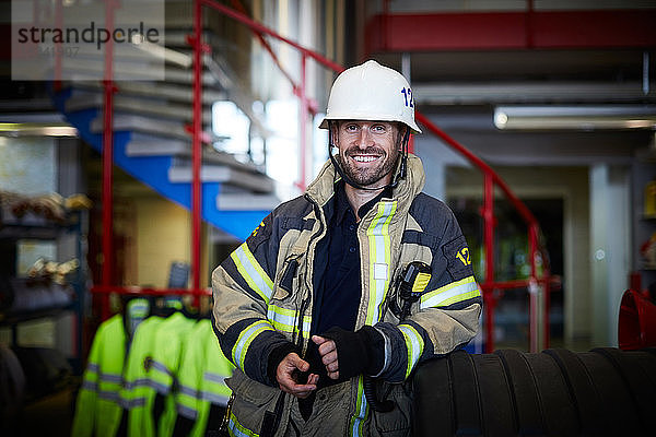 Porträt eines lächelnden Feuerwehrmannes mit Schutzanzug auf der Feuerwache