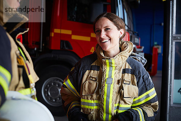 Lächelnde Feuerwehrfrau sieht Mitarbeiterin bei der Kommunikation in der Feuerwache an