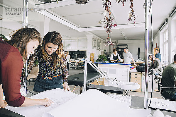 Unternehmerinnen diskutieren über Papier am Tisch im Kreativbüro