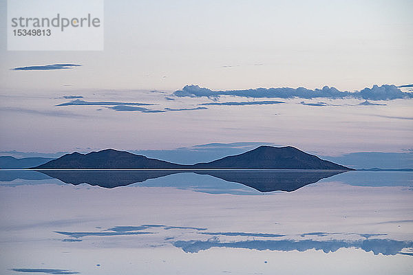 Pastellfarbene Schönheit der Salinen  in denen sich die Wolken und Berge nach Regenfällen kurz nach Sonnenuntergang spiegeln  Uyuni  Bolivien  Südamerika