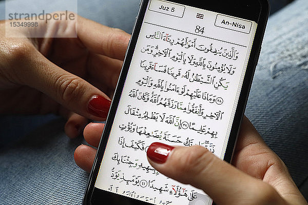 Junge muslimische Frau liest einen digitalen Koran auf einem Smartphone  Vietnam  Südostasien  Asien