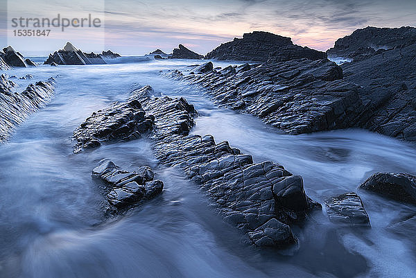 Wellen und nasse Felsvorsprünge am Hartland Quay in North Devon bei Sonnenuntergang  Devon  England  Vereinigtes Königreich  Europa