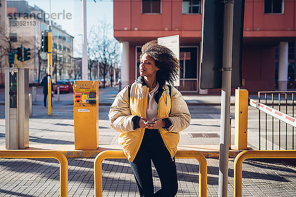 Coole junge Frau wartet an der städtischen Straßenbahnhaltestelle