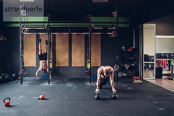 Junge Männer trainieren im Fitnessstudio  machen Liegestütze und Handstand