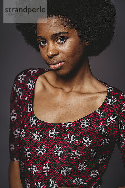 Junge Frau mit afrofarbenen Haaren vor grauem Hintergrund