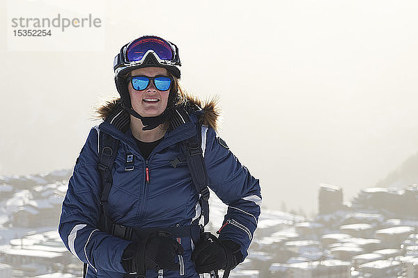 Reife Skifahrerin über schneebedeckten Dächern  Porträt  Alpe-d'Huez  Rhône-Alpes  Frankreich