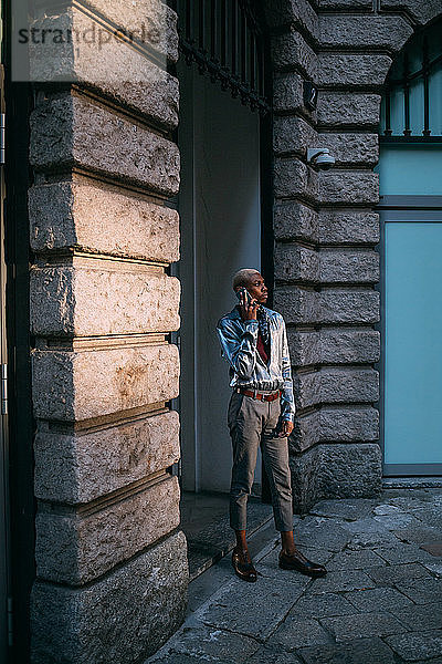Stilvoller Mann benutzt Handy nach Gebäude der Epoche  Mailand  Italien