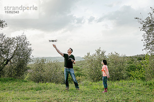 Mädchen beobachtet Vater fliegende Drohne in malerischer Feldlandschaft  Citta della Pieve  Umbrien  Italien