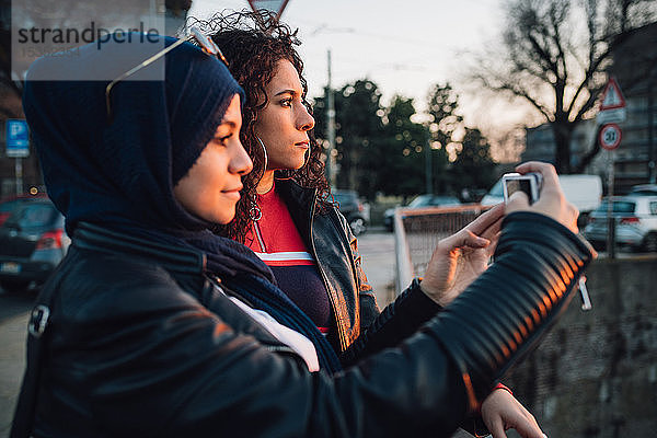 Junge Frau im Hidschab und beste Freundin fotografieren von der Kanalbrücke in der Stadt