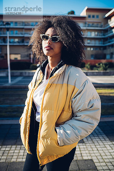 Coole junge Frau mit Sonnenbrille auf städtischem Bürgersteig  Dreiviertelporträt