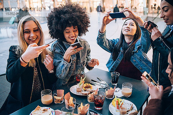 Freunde fotografieren ihr Essen und ihre Getränke im Freiluftcafé  Mailand  Italien