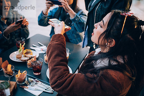 Freunde fotografieren ihr Essen und ihre Getränke im Freiluftcafé  Mailand  Italien