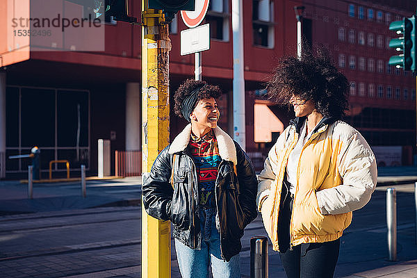 Zwei coole junge Freundinnen unterhalten sich auf einer städtischen Straße