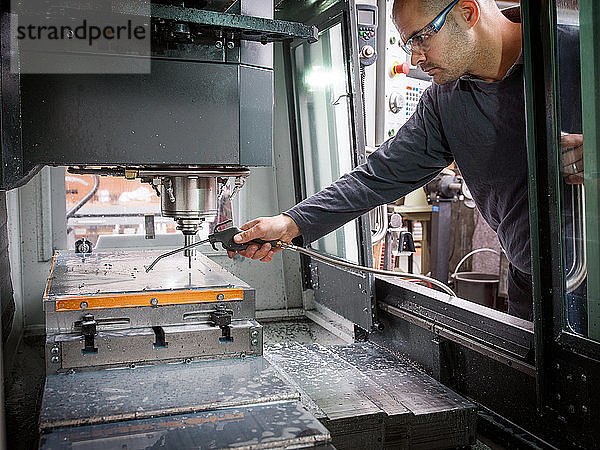 Messerfabrikarbeiter sprüht Flüssigkeit auf Maschinen in der Werkstatt
