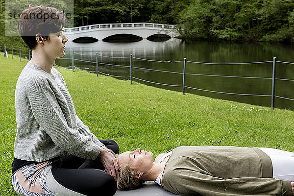 Frau praktiziert Reiki auf Rasen am Fluss  London  UK