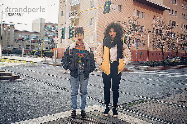 Zwei coole junge Frauen stehen an der städtischen Straßenbahnlinie