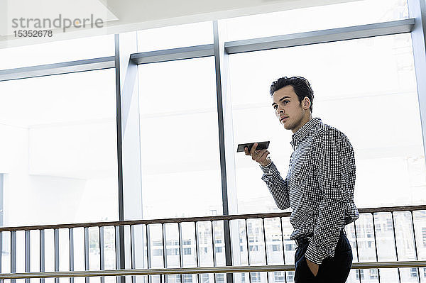 Geschäftsmann benutzt Smartphone im Bürokorridor