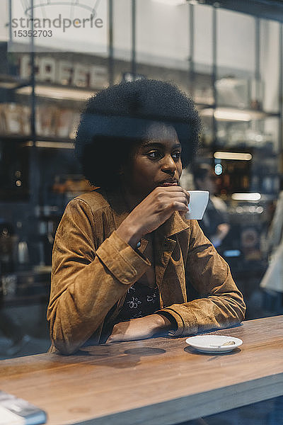 Junge Frau mit Afro-Haaren beim Kaffeetrinken im Café