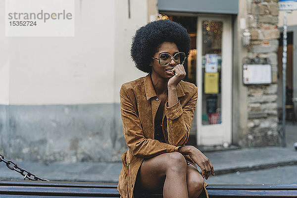 Junge Frau mit Afro-Haaren wartet vor dem Geschäft