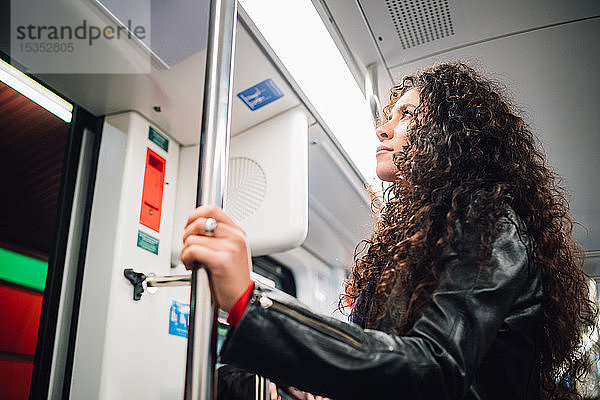 Mittelgroße erwachsene Frau mit langem lockigem Haar in der U-Bahn