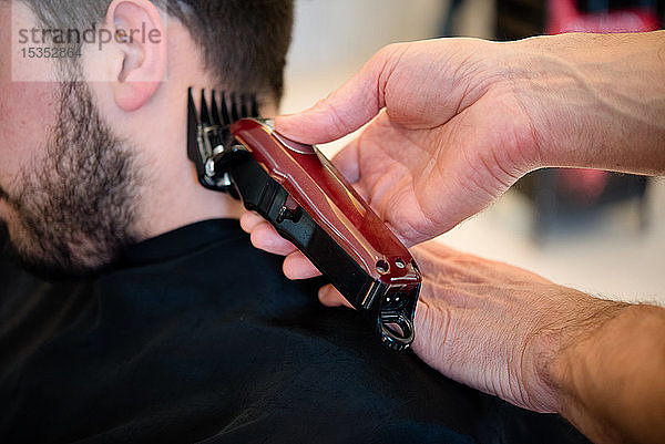 Friseur rasiert Kunden in Friseursalon