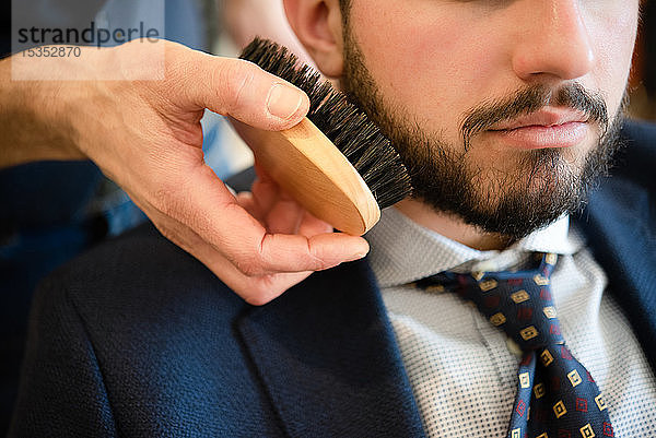 Friseur bürstet Kunden im Friseursalon den Bart