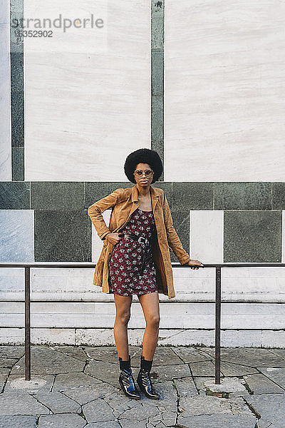 Junge Frau mit Afro-Haaren ruht in der Stadt am Geländer