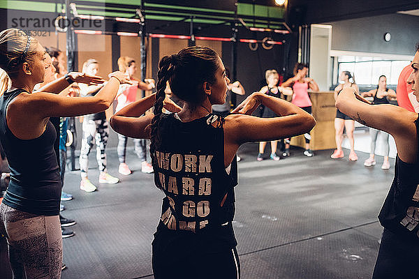 Gruppe von Frauen trainiert im Fitnessstudio  mit erhobenen Armen