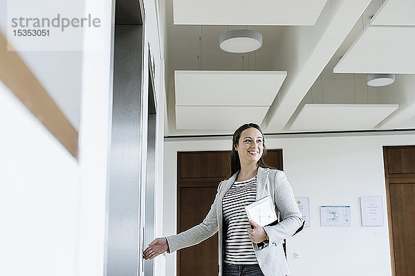 Geschäftsfrau mit digitaler Tablett-Drucktaste des Aufzugs