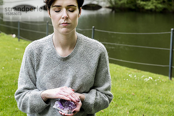 Frau praktiziert Reiki auf Rasen am Fluss  London  UK