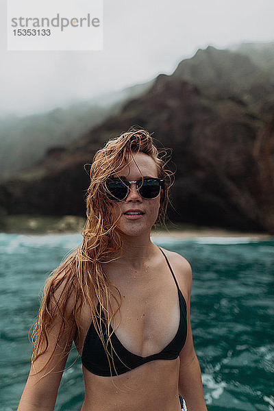 Frau mit Sonnenbrille und Bikini am Meer  Berge im Hintergrund  Princeville  Hawaii  USA